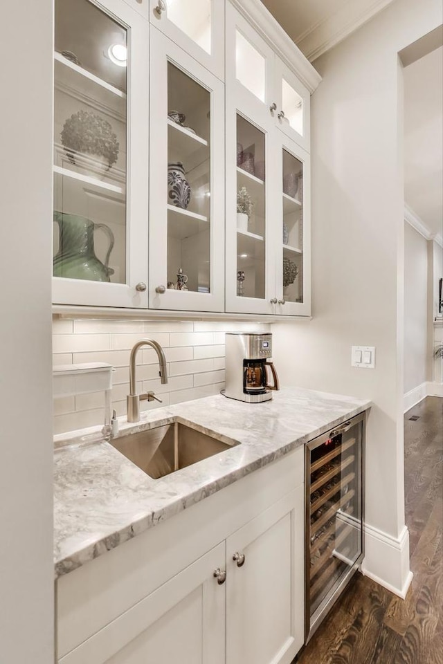 bar featuring a sink, crown molding, beverage cooler, dark wood finished floors, and tasteful backsplash