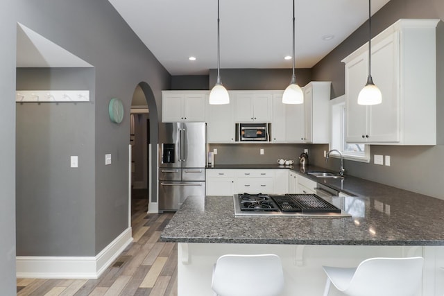 1314 E Washington St, Bloomington, IL 61701 - kitchen with arched walkways, light wood-type flooring, a sink, a peninsula, and stainless steel appliances