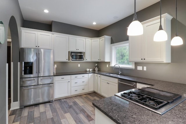 1314 E Washington St, Bloomington, IL 61701 - kitchen with appliances with stainless steel finishes, a sink, arched walkways, white cabinetry, and light wood-type flooring