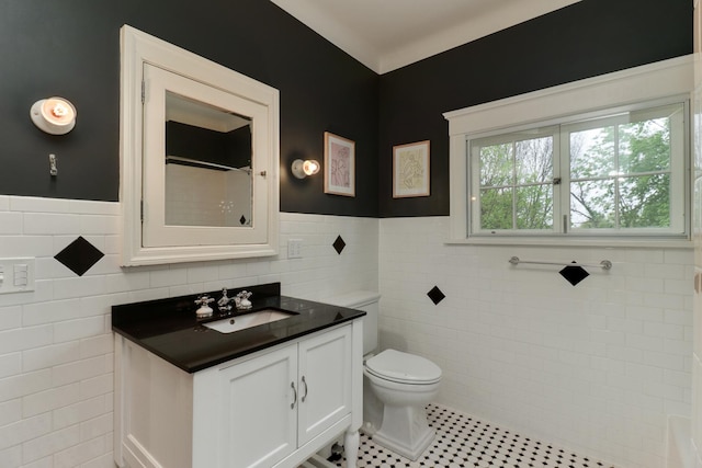 1314 E Washington St, Bloomington, IL 61701 - bathroom featuring vanity, wainscoting, toilet, tile walls, and tile patterned floors