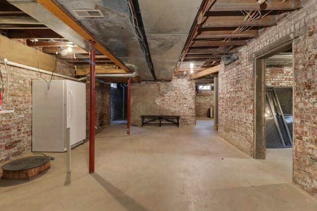 1314 E Washington St, Bloomington, IL 61701 - below grade area featuring freestanding refrigerator, brick wall, and visible vents