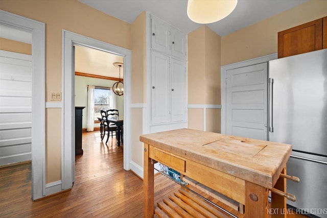 kitchen featuring baseboards, freestanding refrigerator, wood finished floors, and an inviting chandelier