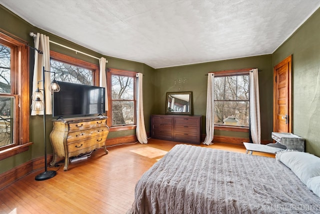 bedroom featuring wood-type flooring, baseboards, and multiple windows