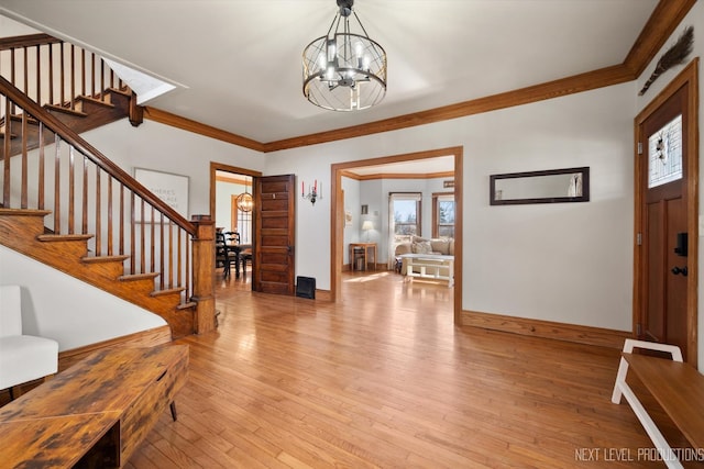 foyer with crown molding, a notable chandelier, baseboards, light wood-type flooring, and stairway