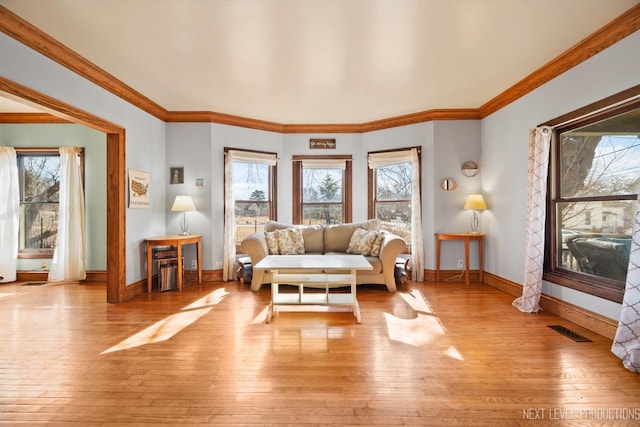 living area featuring visible vents, light wood-style flooring, baseboards, and a healthy amount of sunlight