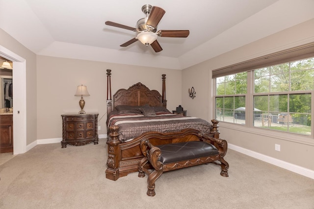 carpeted bedroom featuring a tray ceiling, baseboards, and a ceiling fan