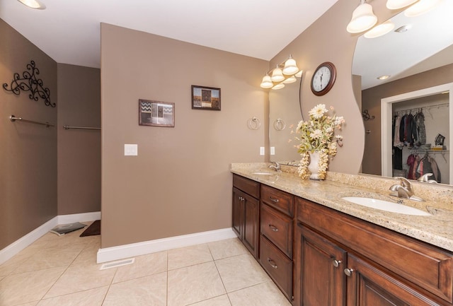 full bathroom featuring baseboards, double vanity, tile patterned floors, and a walk in closet