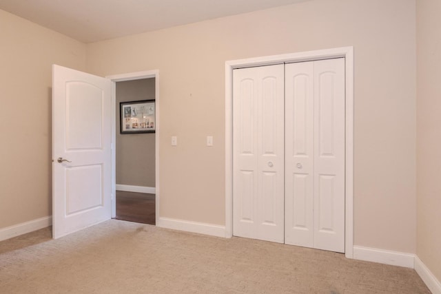 unfurnished bedroom with carpet floors, a closet, and baseboards