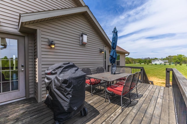 deck featuring outdoor dining space, grilling area, and a lawn