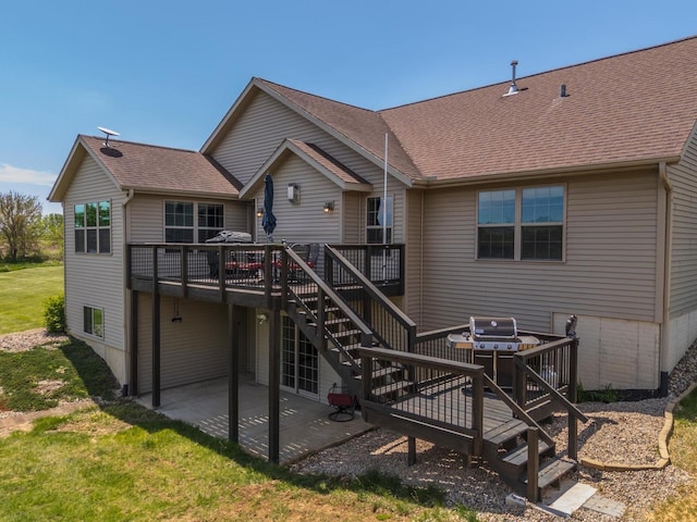back of property featuring a wooden deck, stairway, a patio area, and a shingled roof