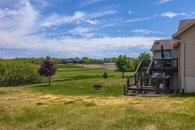 view of green lawn featuring a deck and stairway