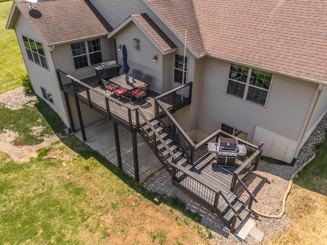 back of property with a shingled roof, a deck, stairs, and a yard