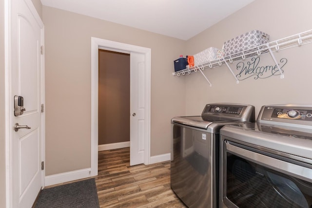 laundry room with washing machine and clothes dryer, wood finished floors, and baseboards