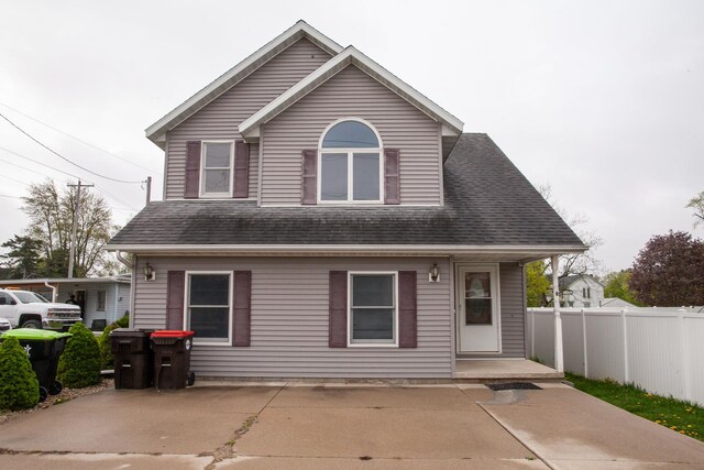 rear view of house featuring roof with shingles and fence