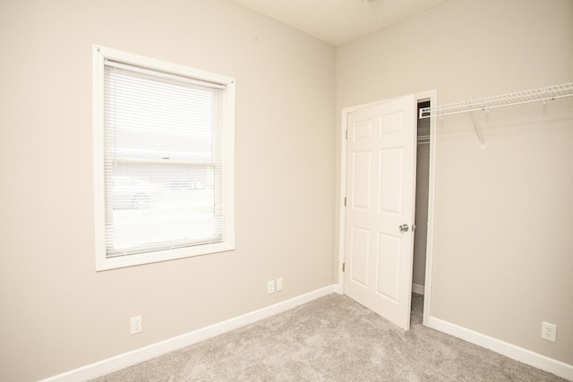 unfurnished bedroom featuring baseboards, light carpet, and a closet