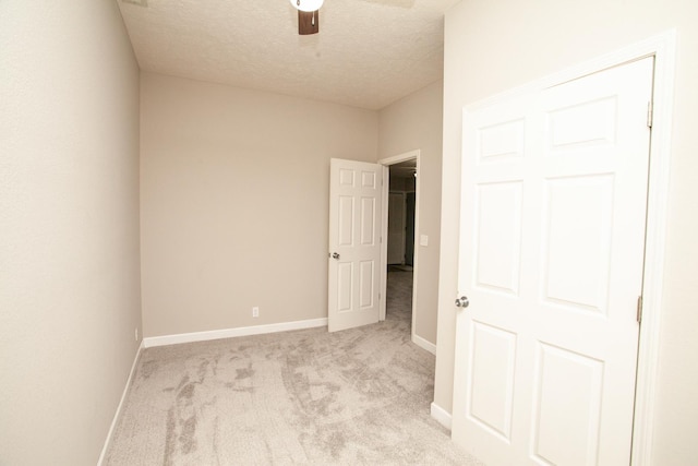 unfurnished bedroom with baseboards, a textured ceiling, ceiling fan, and light carpet
