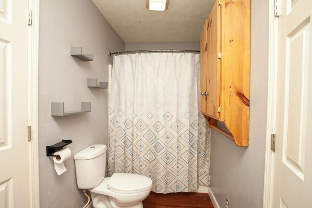 bathroom with toilet, baseboards, curtained shower, and wood finished floors