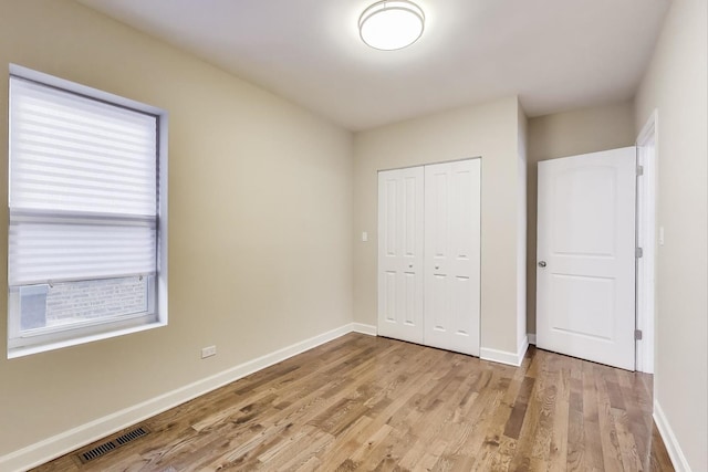 7955 S Paxton Ave, Chicago, IL 60617 - unfurnished bedroom with visible vents, baseboards, a closet, and light wood-type flooring