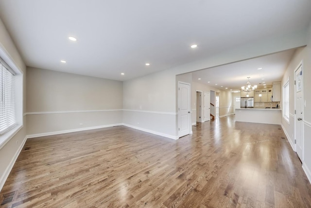 7955 S Paxton Ave, Chicago, IL 60617 - unfurnished living room featuring visible vents, baseboards, a notable chandelier, recessed lighting, and light wood-style flooring