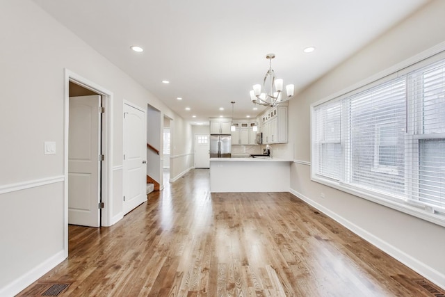 7955 S Paxton Ave, Chicago, IL 60617 - kitchen featuring glass insert cabinets, appliances with stainless steel finishes, light countertops, a peninsula, and an inviting chandelier
