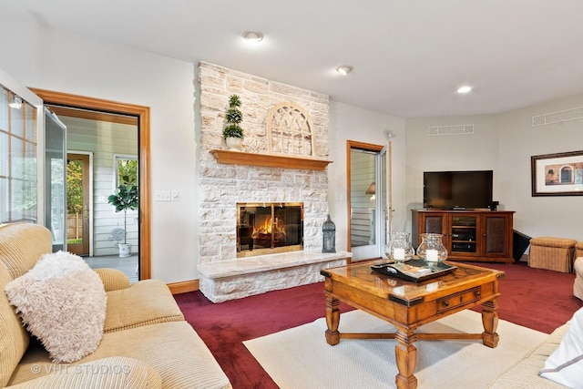 carpeted living room featuring visible vents and a stone fireplace
