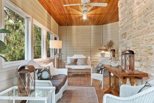 sunroom / solarium featuring a ceiling fan, hardwood / wood-style floors, wood walls, and wood ceiling