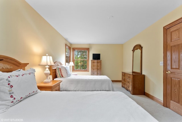 bedroom featuring light carpet and baseboards