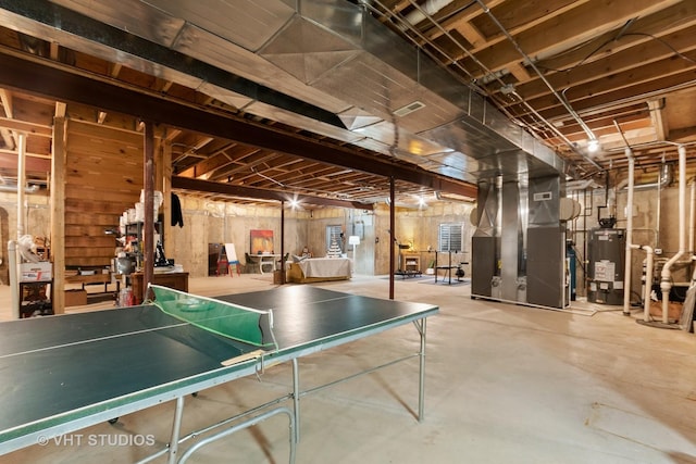 rec room with visible vents, heating unit, unfinished concrete flooring, and gas water heater