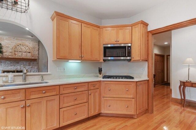 kitchen with light wood-style floors, stainless steel appliances, light countertops, and a sink
