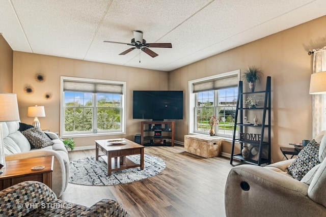 living room with baseboards, ceiling fan, and wood finished floors