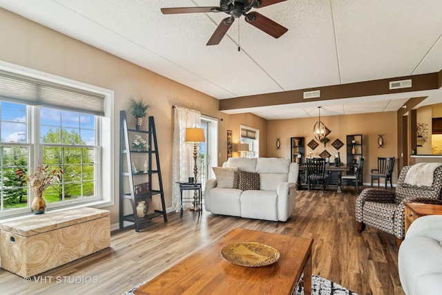 living room with visible vents, ceiling fan with notable chandelier, and wood finished floors