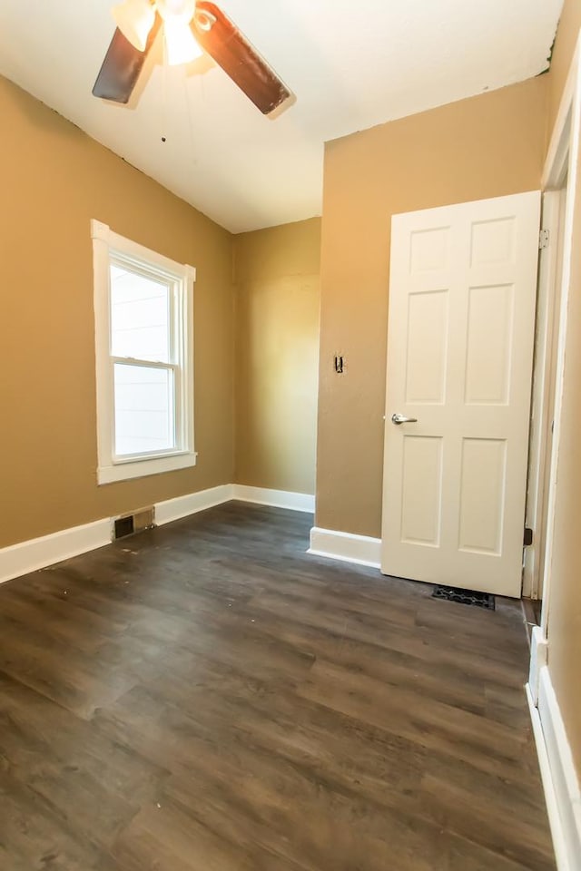unfurnished room with baseboards, ceiling fan, dark wood-style floors, and visible vents