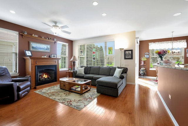 12951 Bull Ridge Dr, Huntley, IL 60142 - living room with plenty of natural light, baseboards, ceiling fan with notable chandelier, a glass covered fireplace, and light wood-style flooring