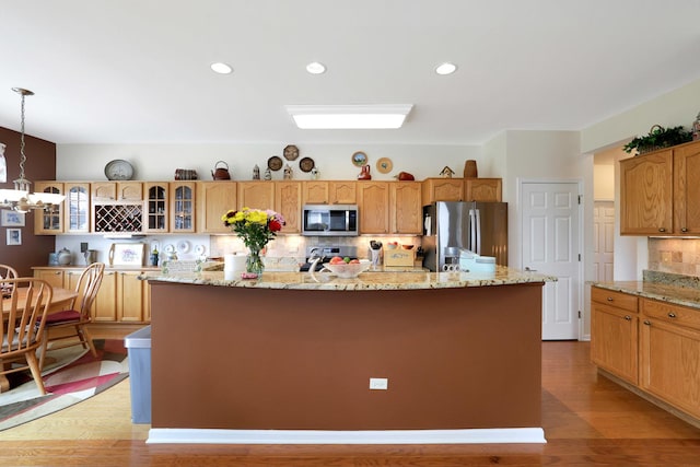 12951 Bull Ridge Dr, Huntley, IL 60142 - kitchen featuring decorative backsplash, appliances with stainless steel finishes, a center island with sink, glass insert cabinets, and light wood-style flooring