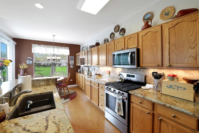 12951 Bull Ridge Dr, Huntley, IL 60142 - kitchen with light wood-type flooring, tasteful backsplash, a sink, a notable chandelier, and stainless steel appliances