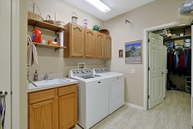12951 Bull Ridge Dr, Huntley, IL 60142 - laundry room featuring washing machine and clothes dryer, cabinet space, a sink, baseboards, and light wood-style flooring