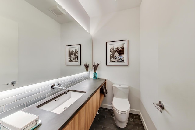 half bathroom featuring vanity, toilet, baseboards, decorative backsplash, and visible vents