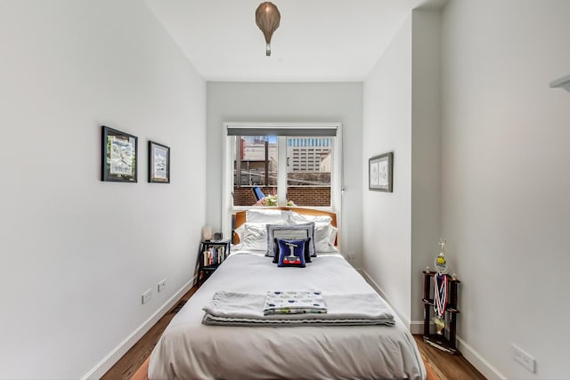 bedroom with baseboards and dark wood-type flooring