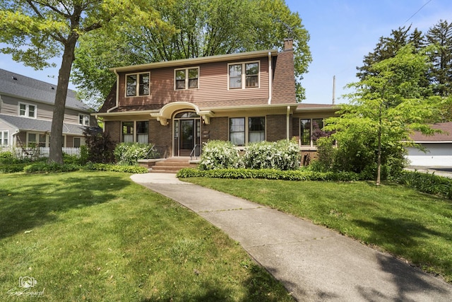 view of front of house with a chimney, a front lawn, and brick siding