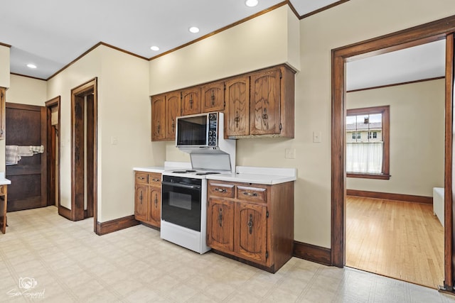kitchen with electric range oven, crown molding, baseboards, light countertops, and brown cabinets