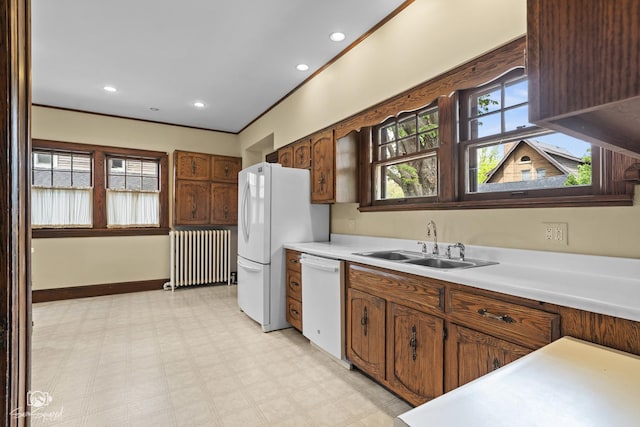 kitchen featuring radiator, white appliances, a sink, light flooring, and light countertops