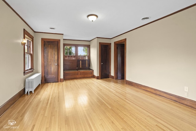 spare room with radiator heating unit, ornamental molding, baseboards, and light wood finished floors