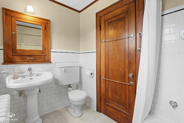 full bathroom with a shower with shower curtain, tile walls, ornamental molding, toilet, and wainscoting