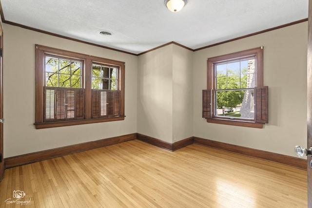 unfurnished room featuring baseboards, light wood-style floors, and crown molding