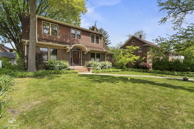 view of front of house with a chimney, a front yard, and brick siding