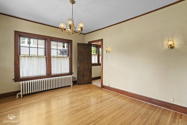 spare room featuring radiator, baseboards, a chandelier, crown molding, and light wood-style floors