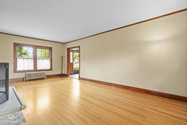 unfurnished living room featuring radiator, light wood-style floors, ornamental molding, and baseboards
