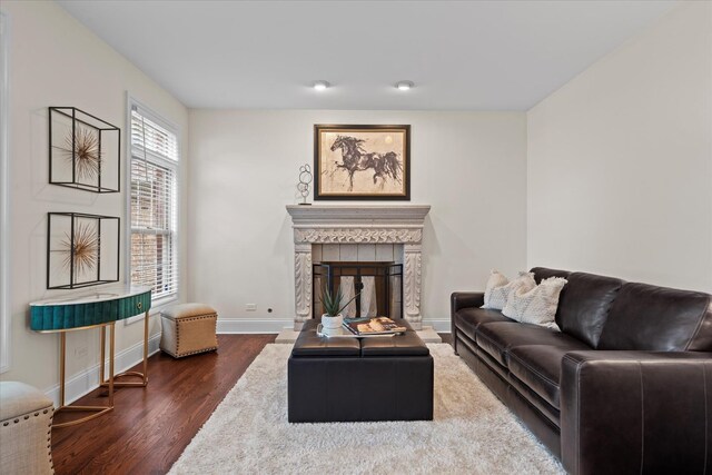 living room featuring baseboards, dark wood finished floors, and a tile fireplace
