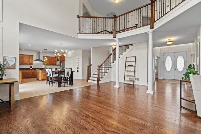 living area featuring light wood-style floors, decorative columns, a high ceiling, and stairway