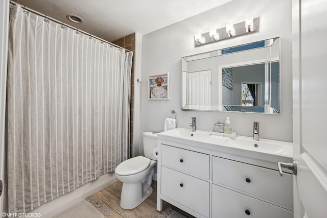 bathroom featuring toilet, wood finished floors, and vanity